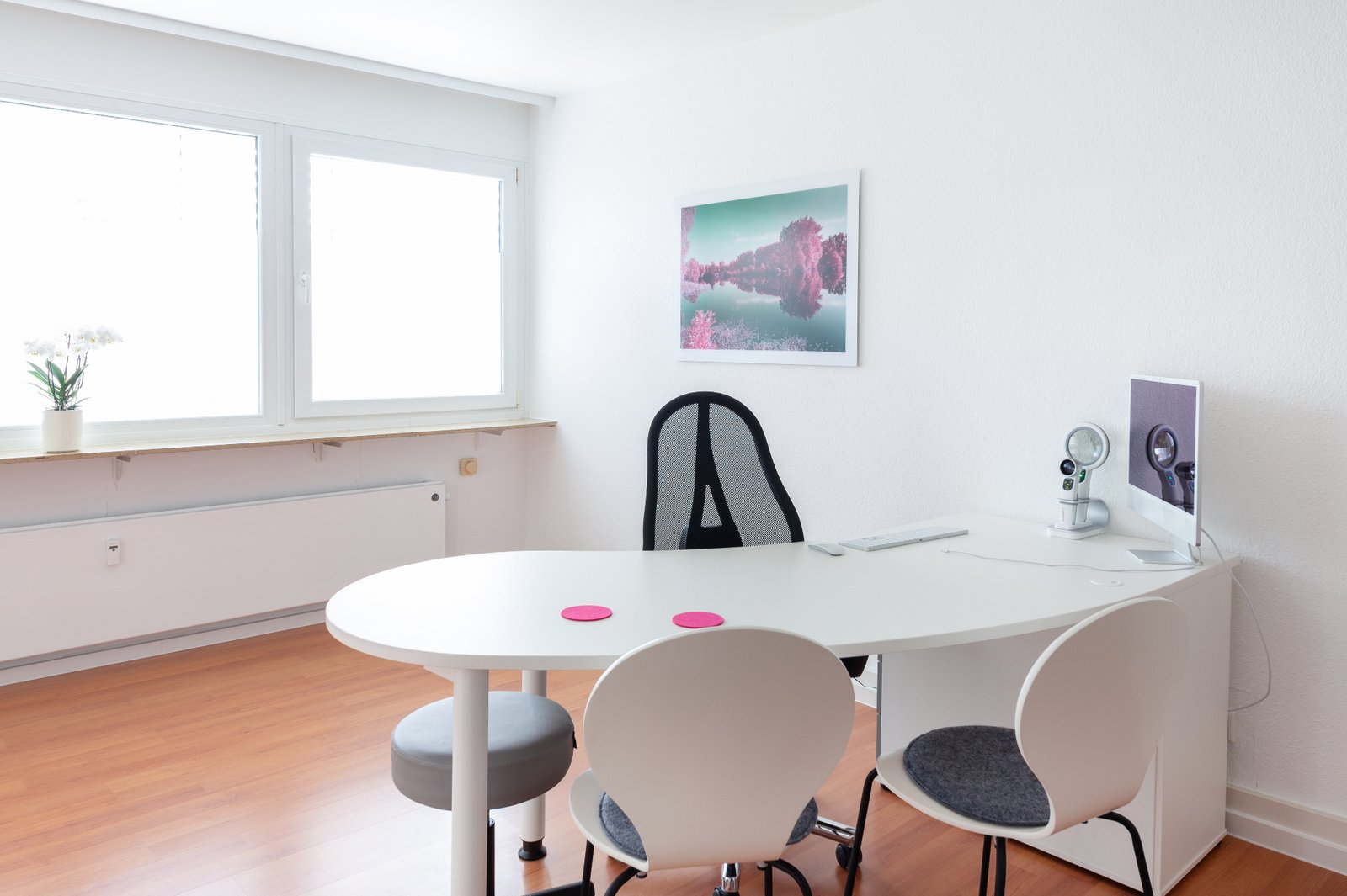 Helles Sprechzimmer der Praxis mit ovalem Tisch und Untersuchungsgeräten